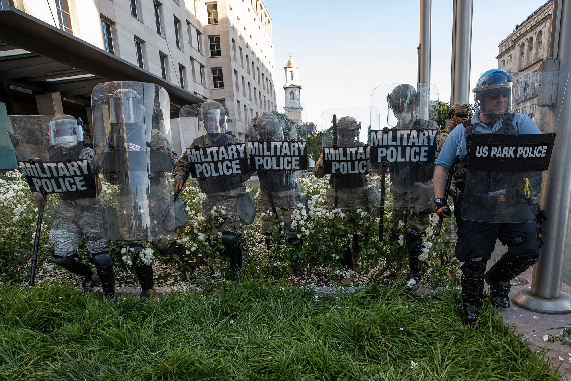 In this June 1, 2020, file photo, District of Columbia National Guard, and U.S. Park Police, advance through the white roses in front of the AFL-CIO headquarters, with St. John's Church behind them, as they move demonstrators back after they gathered to protest the death of George Floyd near the White House in Washington.