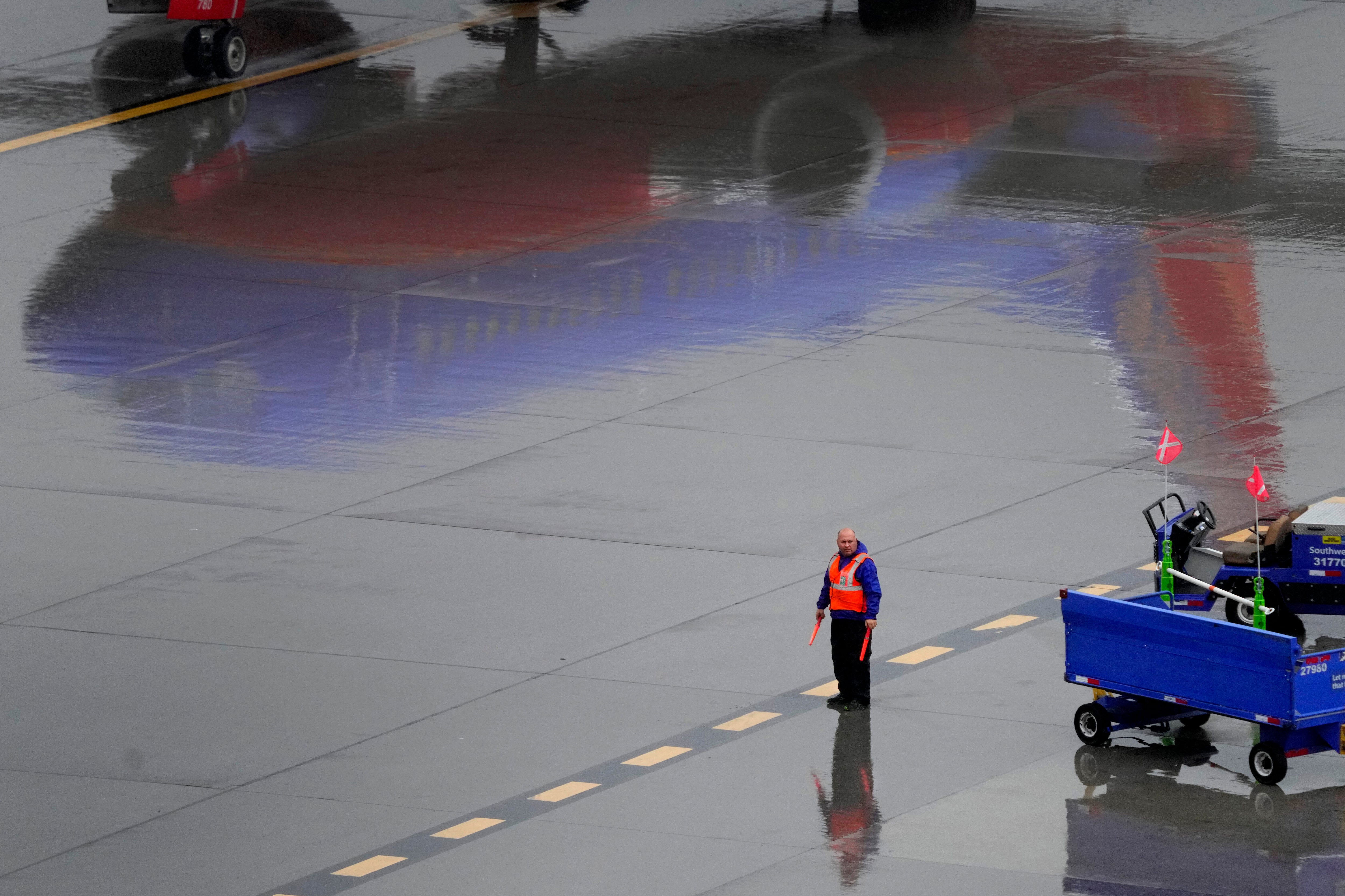 A Southwest Airlines ground operations crew member waits to guide an arriving jet into a gate, Wednesday, Dec. 28, 2022, at Sky Harbor International Airport in Phoenix.