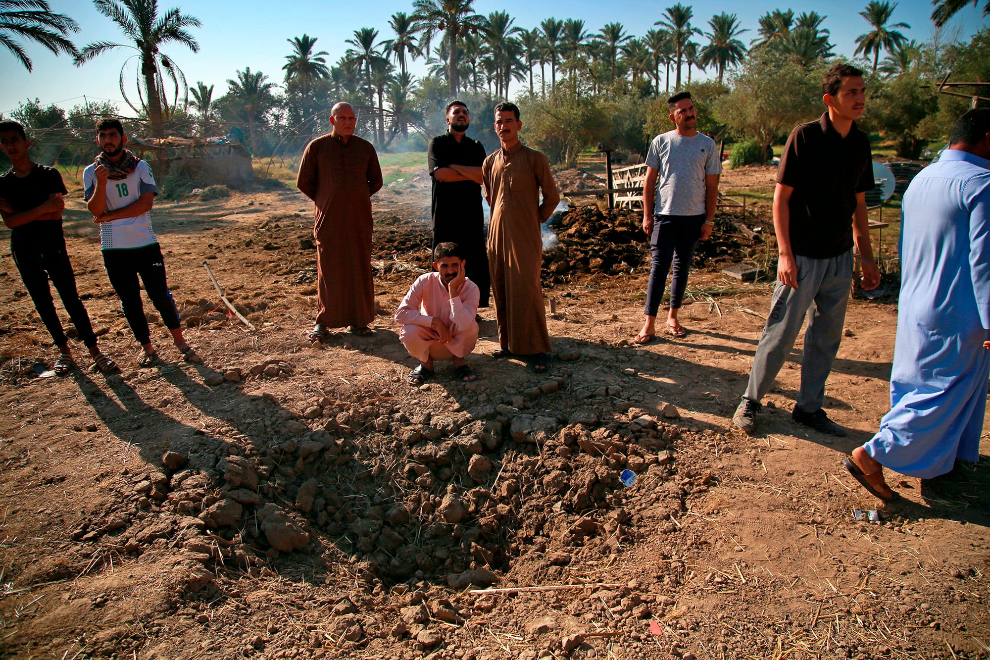 People inspect a crater caused by a deadly Katyusha rocket attack near international airport in Baghdad, Iraq, Tuesday, Sept. 29, 2020.