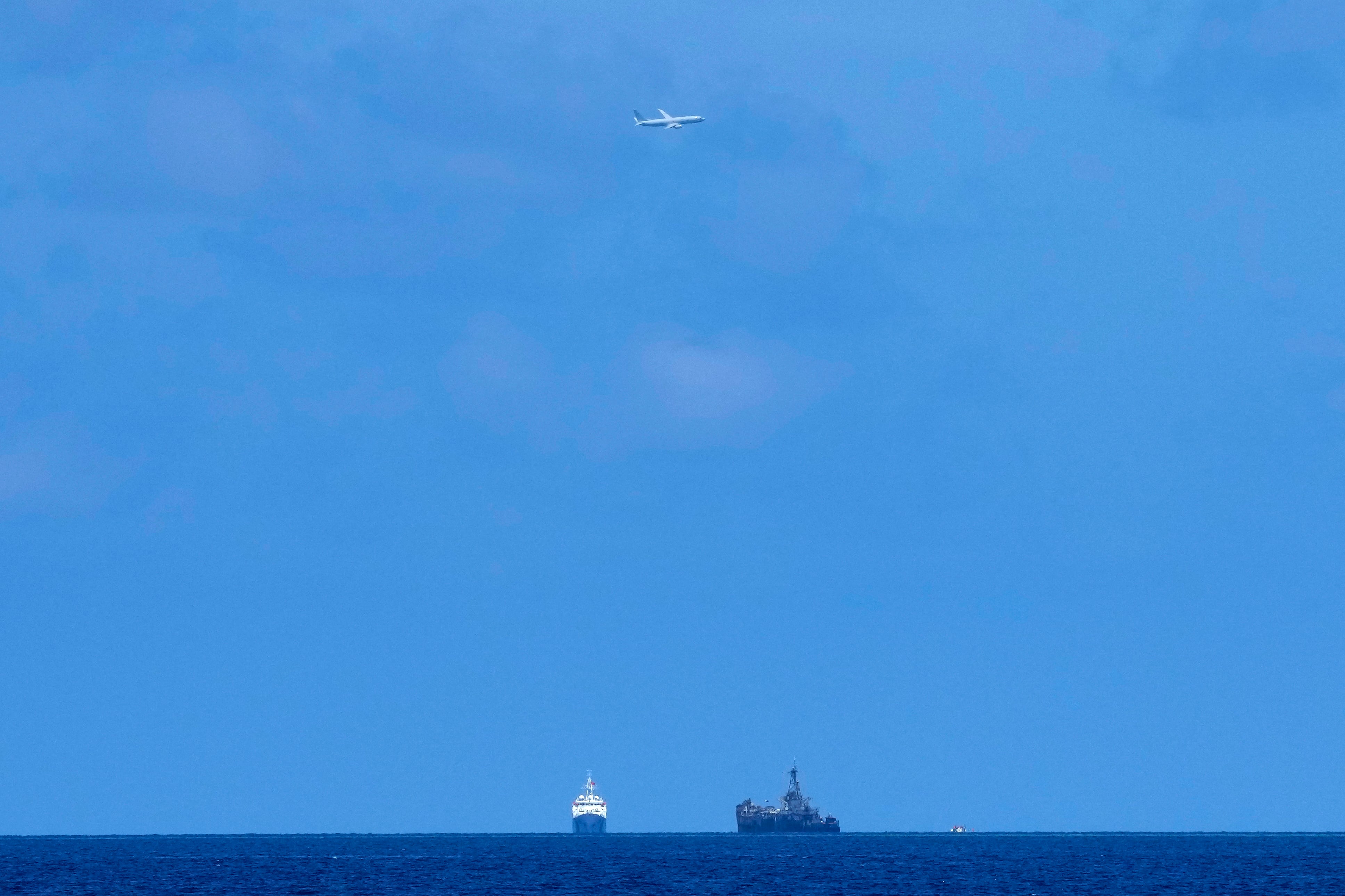 A U.S. Navy plane flies over BRP Sierra Madre, right, and Chinese coast guard ship at the Second Thomas Shoal, locally known as Ayungin Shoal, at the disputed South China Sea on Tuesday, Aug. 22, 2023.