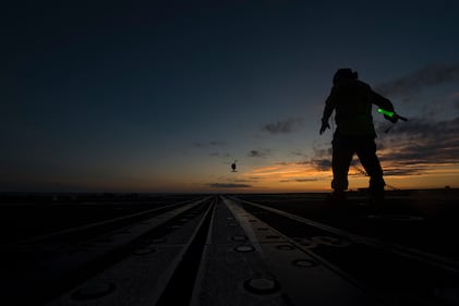 Navy Boatswain's Mate Seaman Cristian Martinez directs an MH-60S Sea Hawk helicopter on the flight deck aboard the guided-missile cruiser USS Vella Gulf (CG 72) in the Atlantic Ocean, July 10, 2019.