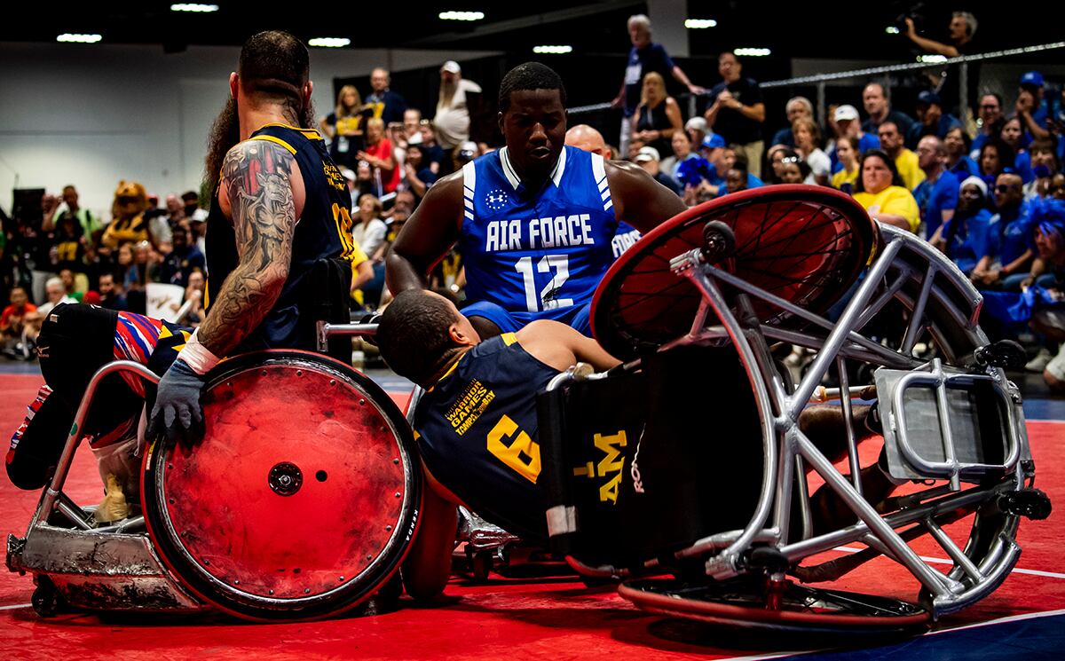 Air Force Senior Airman DeMarcus Garrett, Team Air Force athlete, powers through Team Navy defenders during the Department of Defense Warrior Games wheelchair rugby finals