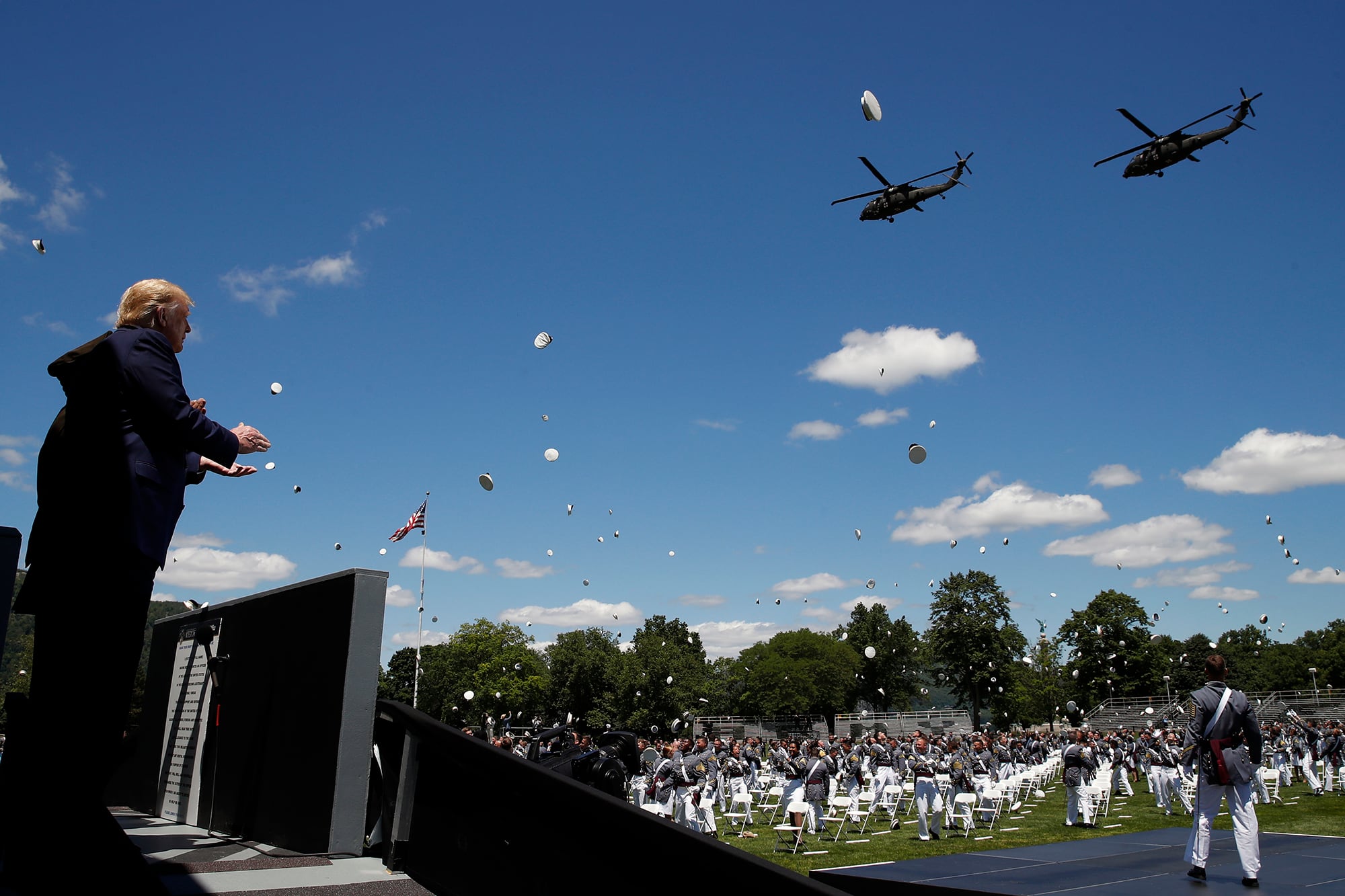 President Donald Trump applauds as Army helicopters fly over and West Point cadets toss their caps into the air at the end of commencement ceremonies on the parade field, at the United States Military Academy in West Point, N.Y., Saturday, June 13, 2020.