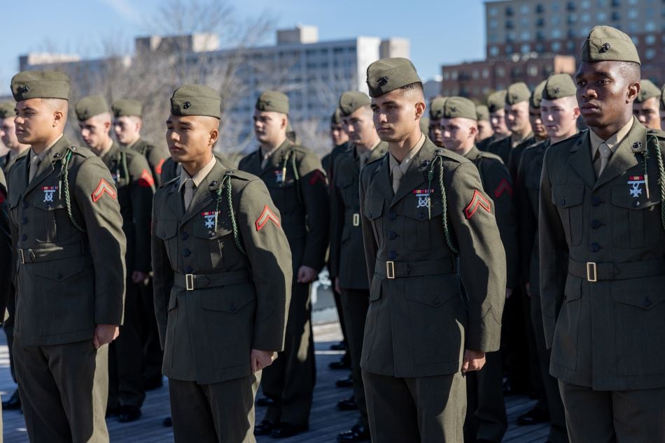 Rows of Marines stand at attention at an outdoor ceremony aboard a ship