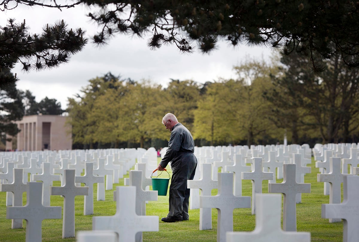 Normandy American Cemetery worker cleans headstones.