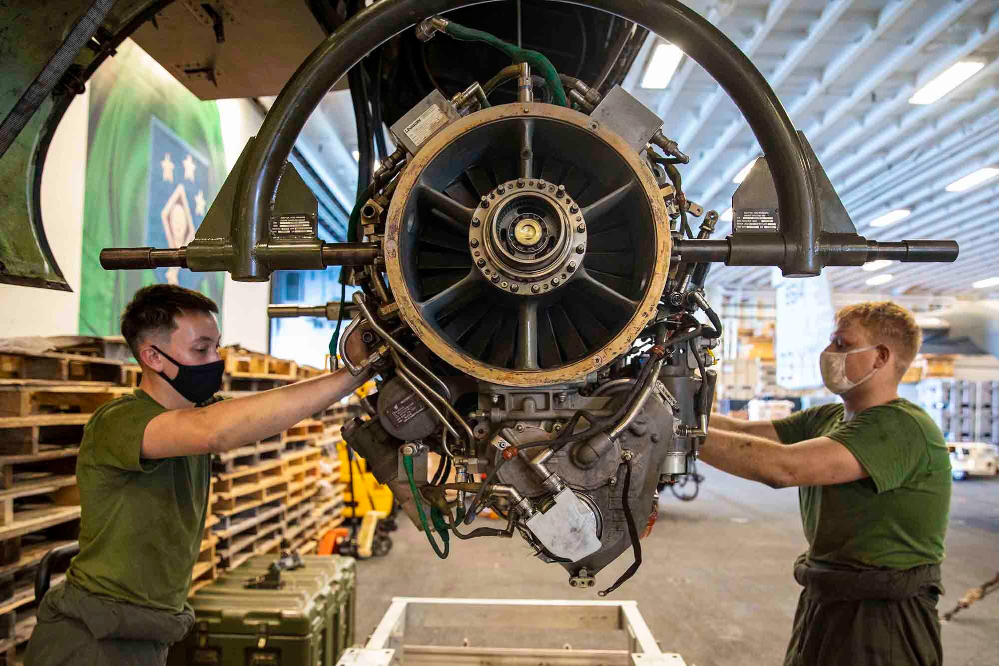 Marine Corps Sgt. William Easter, right, and Lance Cpl. Nathaniel Hinkle remove an engine from an Osprey aboard the amphibious assault ship USS Makin Island (LHD 8) on Jan. 19, 2021, in the Indian Ocean.