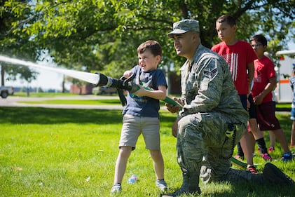 Senior Airman Isaiah Raiano helps a child operate a fire hose during the Summer Youth Fair at Fairchild Air Force Base, Wash., July 25, 2019.